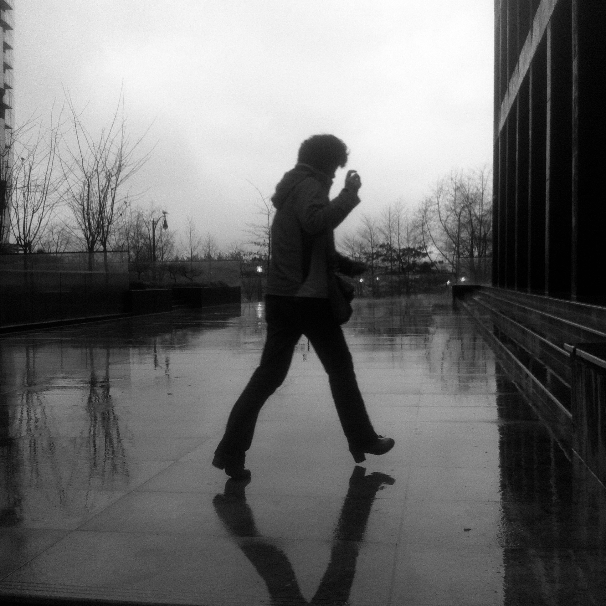 Silhouette of a woman walking on reflective pavement